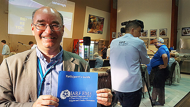 Derek McAuley, EME Chair, holding the participant's guide.