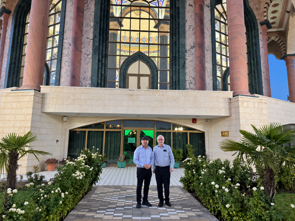Robert Ince and his host stand on the garden path outside the entrance to the Bektashi World Headquarters in Tirana.