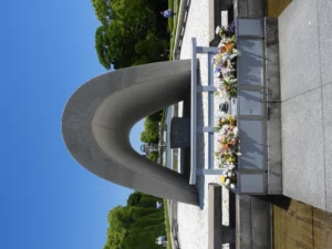 A stone memorial arch framed by floral tributes in a cemetery.